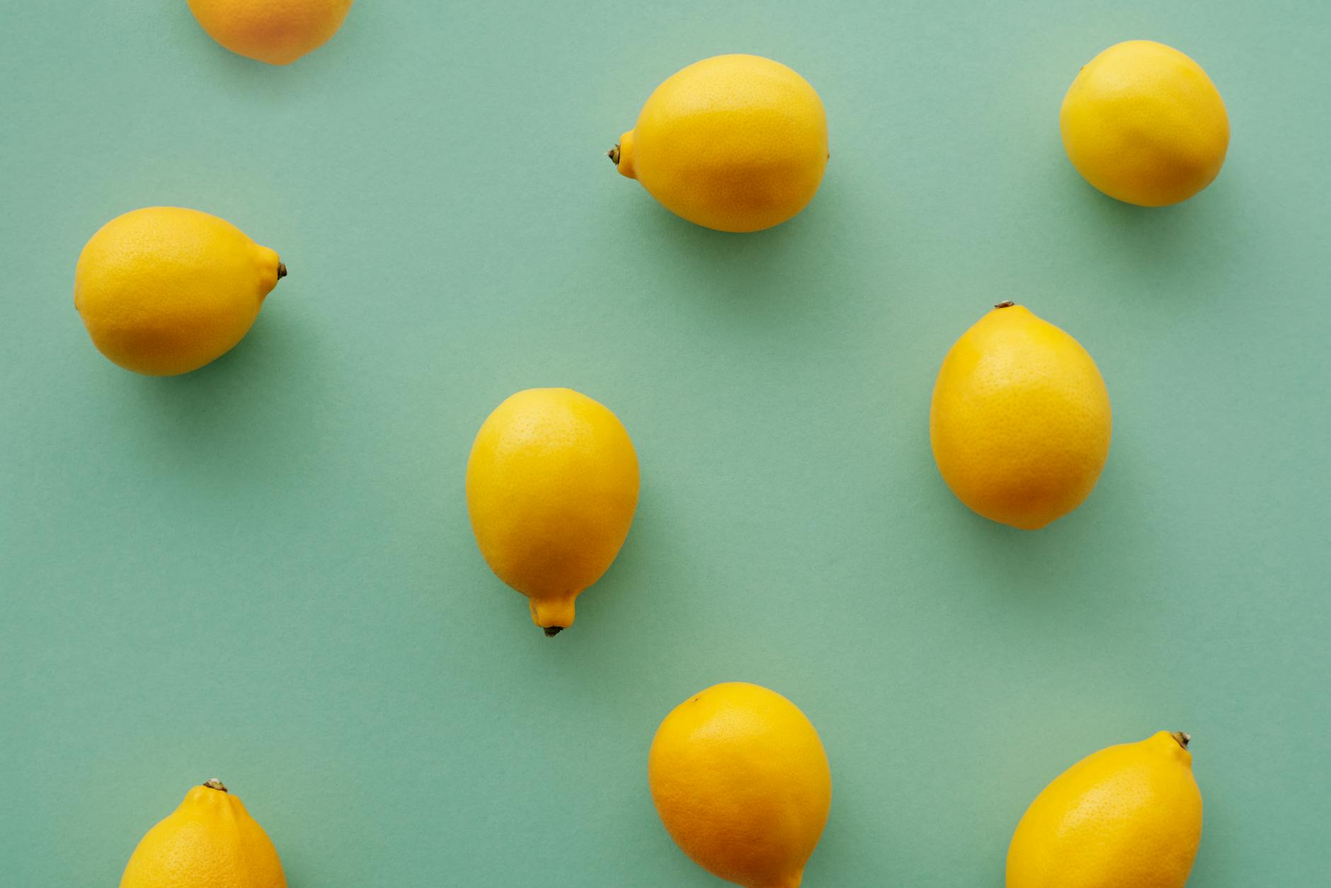 Bright yellow lemons on a pastel green background, symbolizing fresh approaches to pleasure and intimacy