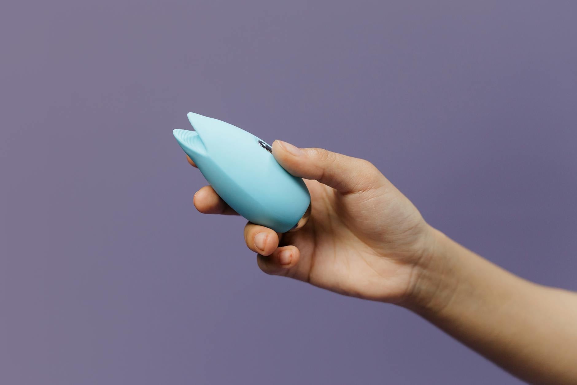Hand holding a fresh lemon against a bright yellow background, symbolizing the gentle suction sensation of a lemon vibrator