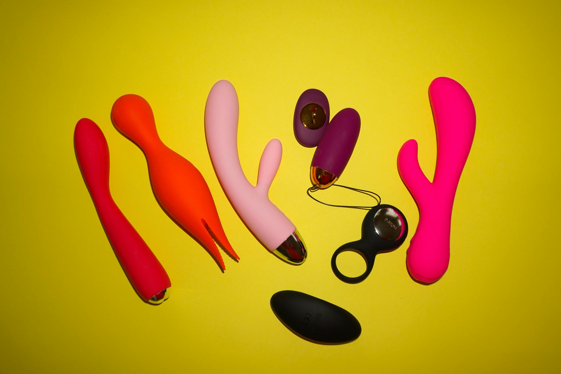 Colorful vibrators and adult toys on a bright yellow background